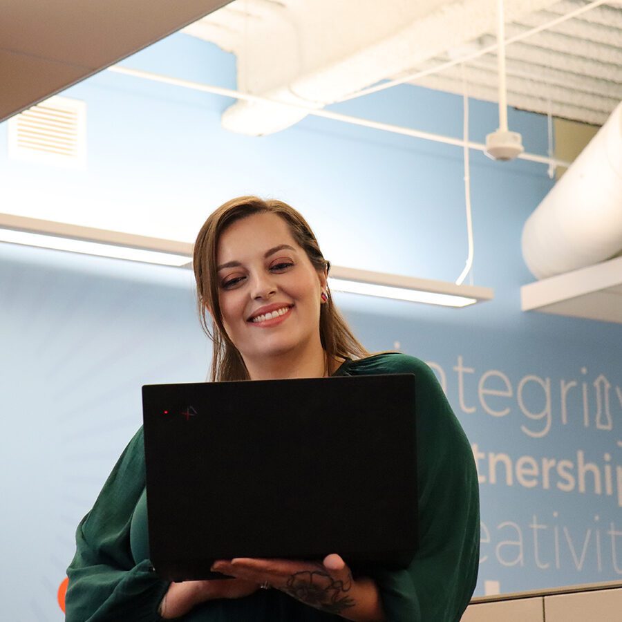 A women is smiling and looking at her laptop