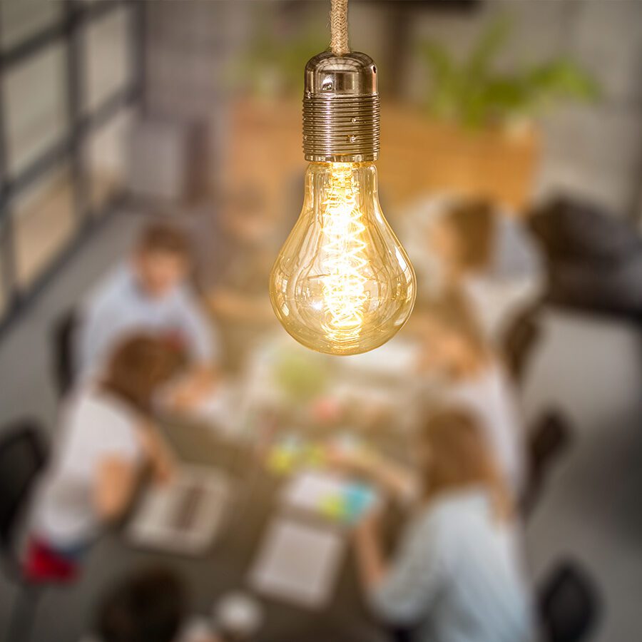 Young business people are discussing together a new startup project. A glowing light bulb as a new idea.