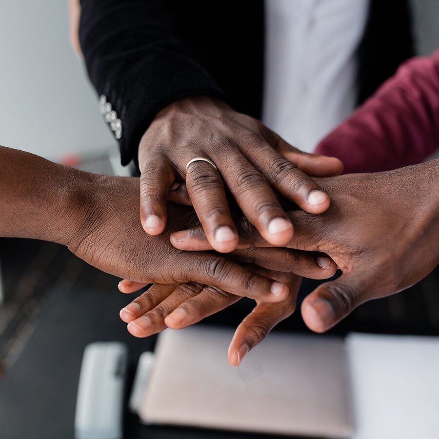 The hands of black people in the center hold each other to unite against racism in large countries.